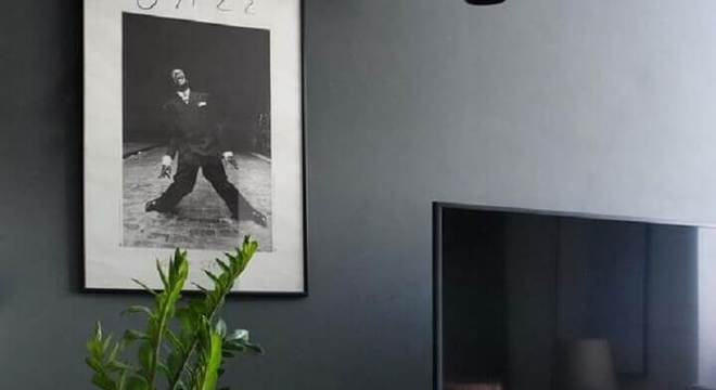 sala com parede cinza escuro e rack de madeira 