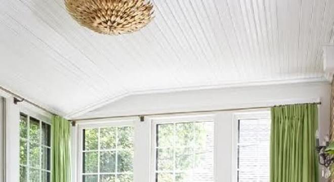 Sala de estar com decoração clean conta com cortinas em tom verde e tapete de sisal