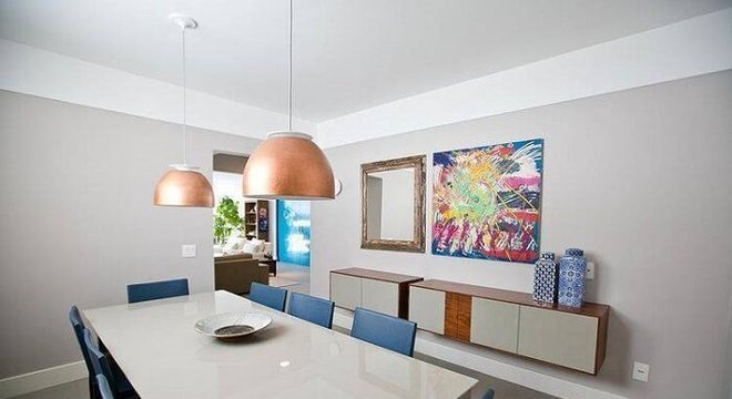 Sala de jantar com mesa retangular branca e cadeiras na cor azul