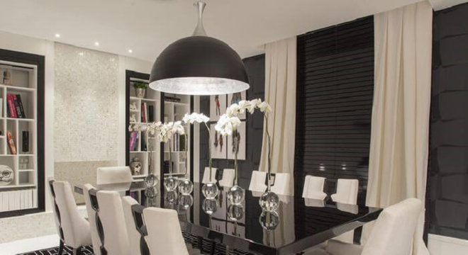Sala de jantar com mesa retangular na cor preta e cadeiras aconchegantes