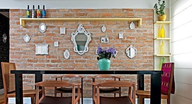 Sala de jantar com parede de tijolinho e cadeira de madeira