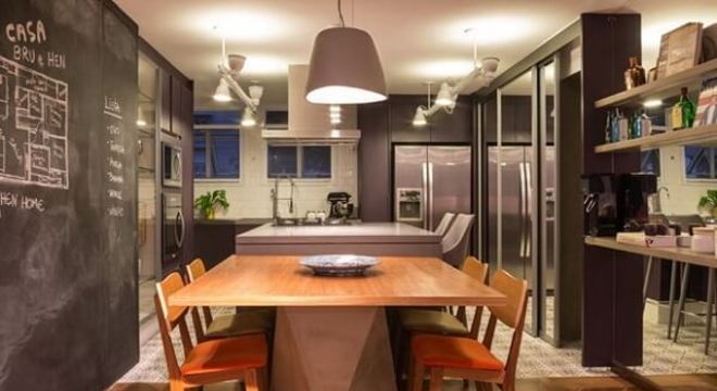 Sala de jantar integrada com a cozinha conta com mesa e cadeira de madeira