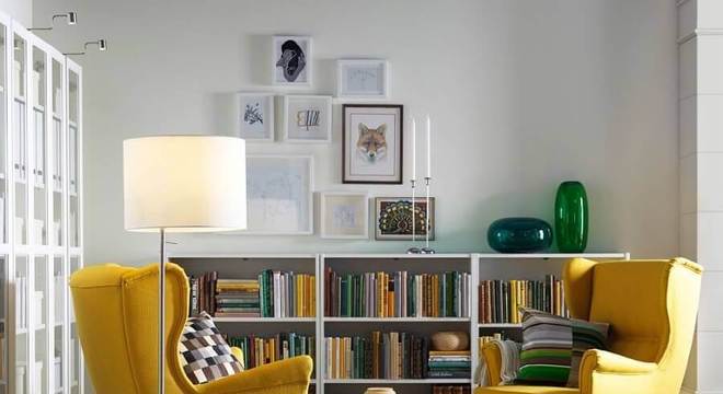 sala decorada com estante pequena para livros e poltronas amarelas