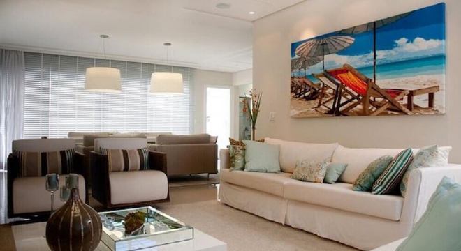 sala toda decorada em tons claros com quadro decorativo grande e colorido