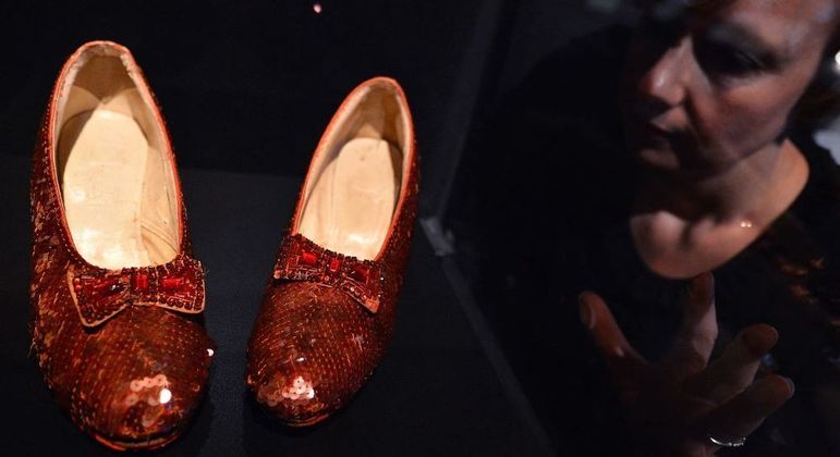 Mulher observa os sapatos usados em O Mágico de Oz numa exposição em 2012