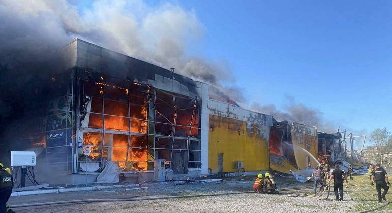 Bombeiros trabalham para conter as chamas em shopping atingido por míssil russo na Ucrânia