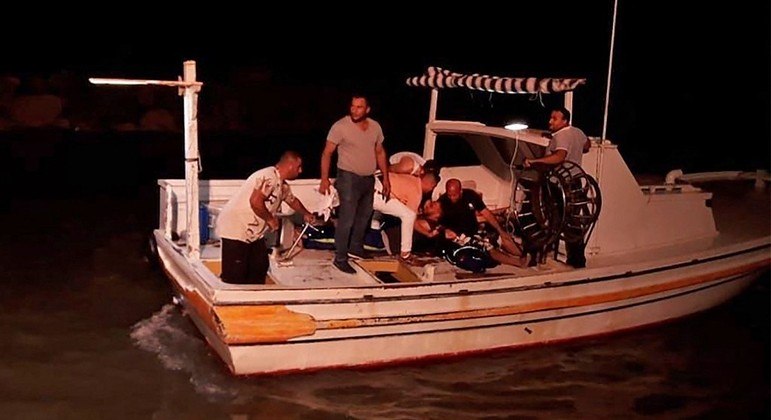 Homens procuram por sobreviventes após barco afundar na costa da Síria