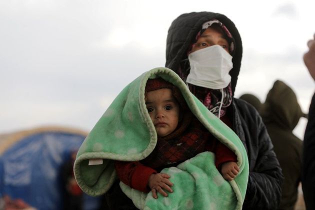 Mulher carrega um bebê em Jindayris, província de Alepo que é dominada por rebeldes