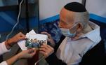 Durante a vacinação,o idoso exibiu fotos suas tiradas durante uma visita ao antigo campo de concentração de Auschwitz, na Polônia