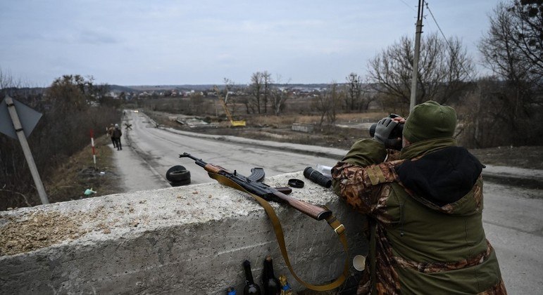 Soldado ucraniano patrulha estrada próxima a Kiev, capital da Ucrânia