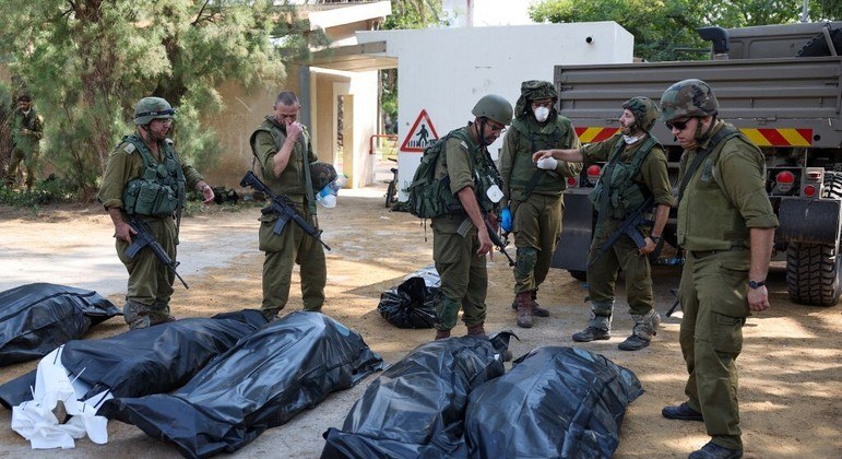 Soldados retiram corpos do kibutz de Kfar Aza, em Israel; cerca de 40 bebês foram encontrados mortos no local
