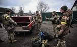 Soldados ucranianos descarregam armas do porta-malas de um carro antigo, a nordeste de Kiev