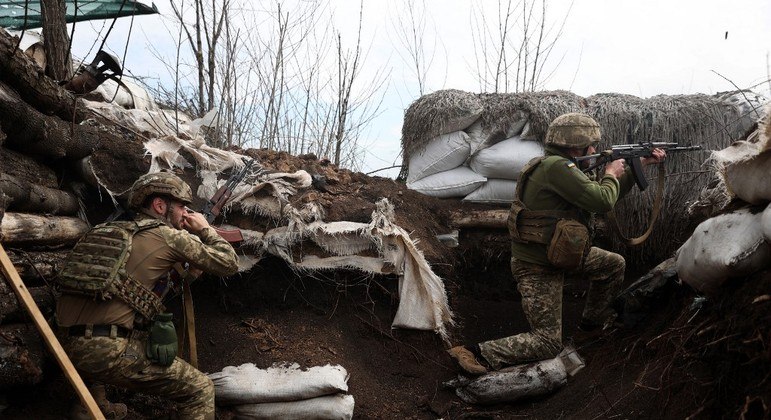 Soldados ucranianos em trincheira atirando contra o exército russo