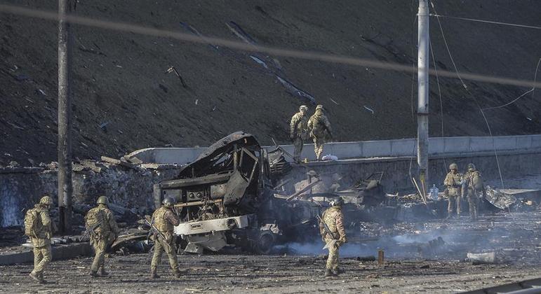 Soldados ucranianos observam veículo destruído após noite de ataques a Kiev