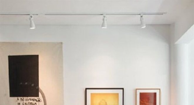 Spot de luz trilho em tom branco complementa a decoração da sala de estar
