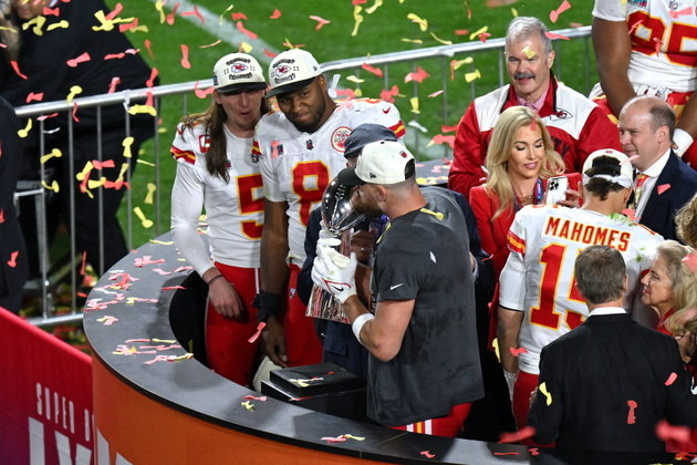 O tight end do Kansas City Chiefs, Travis Kelce, beija o troféu enquanto comemora com sua equipe a vitória no Super Bowl 57 contra o Philadelphia Eagles