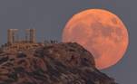 O fenômeno da Lua azul ocorre porque os ciclos lunares duram 28 dias, em vez dos 30 dias de um mês comumAcima, imagem da lua próxima de um templo grego, perto de Atenas, na Grécia