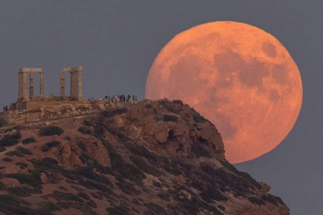 O fenômeno da Lua azul ocorre porque os ciclos lunares duram 28 dias, em vez dos 30 dias de um mês comumAcima, imagem da lua próxima de um templo grego, perto de Atenas, na Grécia