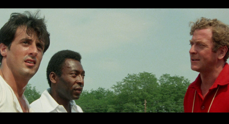 Sylvester Stallone, Pelé e Michael Caine em cena de "Fuga para a Vitória"