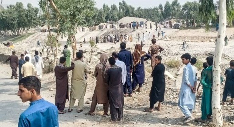 Talibãs e civis se reúnem no local de uma explosão que atingiu uma caminhonete que transportava combatentes