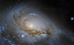 A galáxia em espiral NGC 1961 mostra seus braços desenrolados a partir dos pontos e regiões brilhantes em azul, com estrelas jovens que envolvem o centro da galáxia