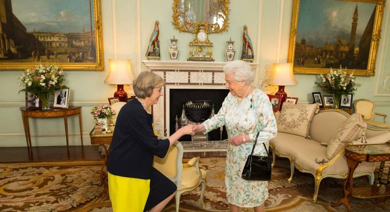 Elizabeth 2ª segura a famosa bolsa em encontro com a ex-primeira-ministra britânica Theresa May