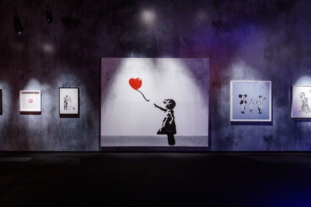 Balloon Girl, uma das obras mais famosas de Banksy, está exposta ao público. São mais de 150 trabalhos do artista em exposição — entre originais certificados, gravuras, fotos, litografias, esculturas, murais, além de instalações feitas especificamente para a exibição.