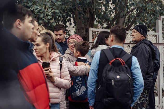 Mulher abraça menino. Eles estão próximos à escola que sofreu um ataque a tiros nesta segunda-feira (26), na Rússia