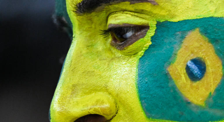 Torcedor pinta o rosto de verde e amarelo para apoiar o Brasil contra a Sérvia na estreia da Copa