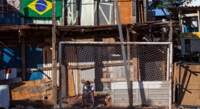 Criança senta-se atrás do gol na favela de São Paulo durante a Copa de 2014
