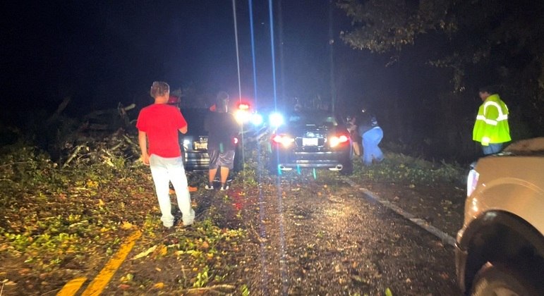 Pessoas ajudam um motorista a mover um carro danificado por galhos bloqueando uma estrada, depois que um tornado arrancou e destruiu várias árvores, perto de Daingerfield, Texas