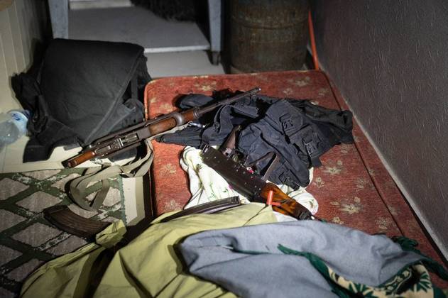 O espaço aparenta ser um alojamento provisório, com colchões espalhados em meio aos armamentos