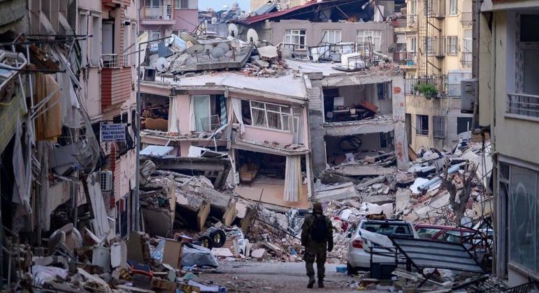 Soldado turco caminha, neste domingo (12), entre prédios destruídos na cidade de Hatay
