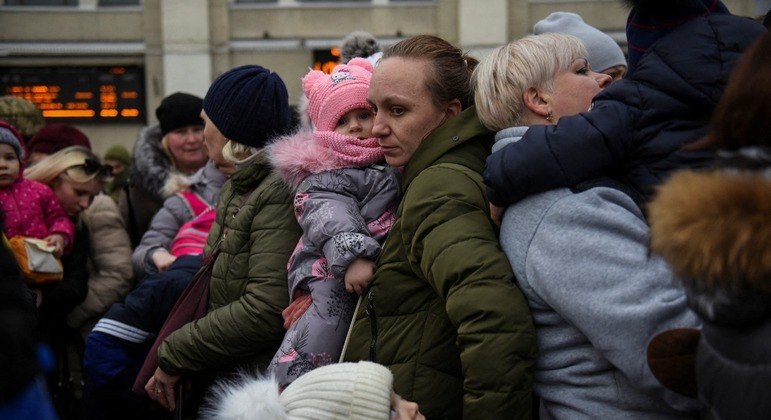 Mulher segura suas filhas enquanto civis fogem da invasão da Ucrânia pela Rússia, em Odessa