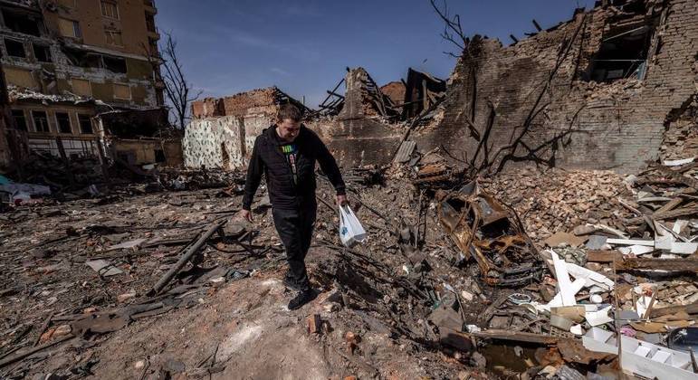 Ucraniano caminha sobre os destroços de prédios atacados pela Rússia em Kharkiv
