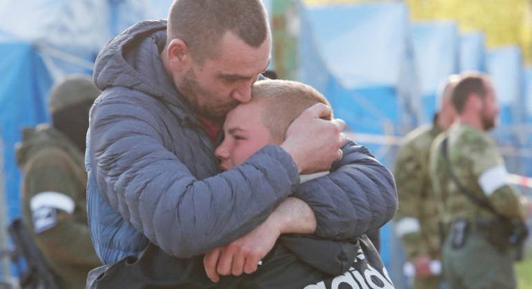 Homem retirado de Azovstal abraça o filho ao chegar à  região de Donetsk