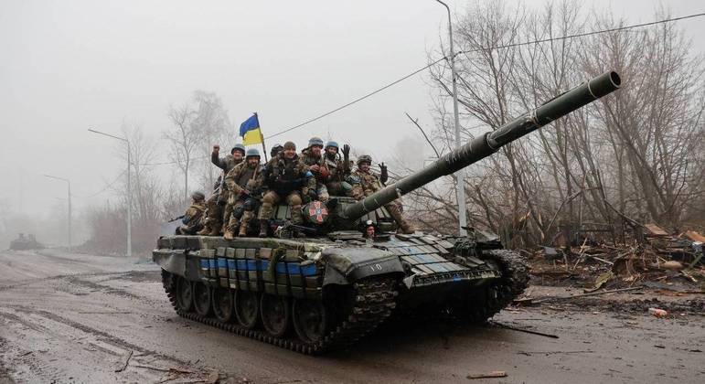 Membros do serviço ucraniano são vistos em cima de um tanque, na região de Chernihiv