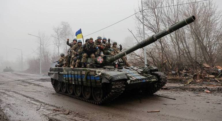 Membros do serviço ucraniano são vistos em cima de um tanque, na região de Chernihiv