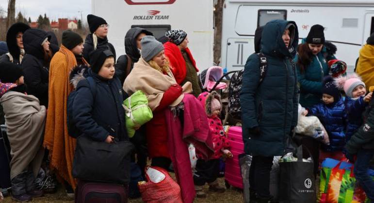 Refugiados ucranianos fazem fila para embarcar em um ônibus para a Estônia