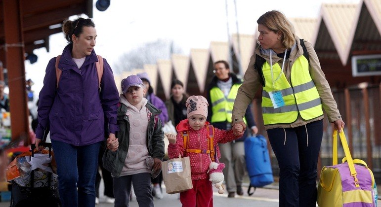 Refugiados ucranianos andam em plataforma após chegar de trem à Polônia