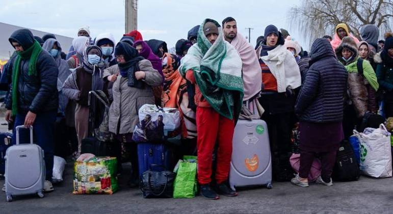 Pessoas que fugiram da Ucrânia esperam para embarcar em um ônibus na Polônia