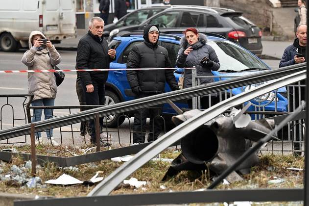 Pessoas reagem em pé atrás da área isolada ao redor dos restos de um projétil em Kiev