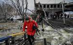 Homem carrega cachorro ao tentar fugir de Kiev atravessando uma ponte destruída após ataques russos