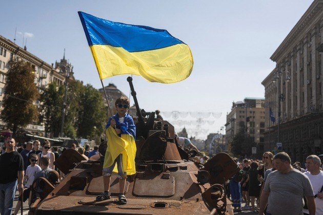 Menino segura bandeira da Ucrânia em cima de um tanque de guerra russo, em Kiev 