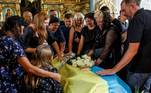 Parentes e amigos choram ao lado de um caixão com o corpo de um militar ucraniano