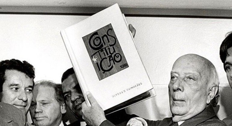 Ulysses Guimarães, presidente da Assembleia Constituinte, apresenta a Constituição de 1988