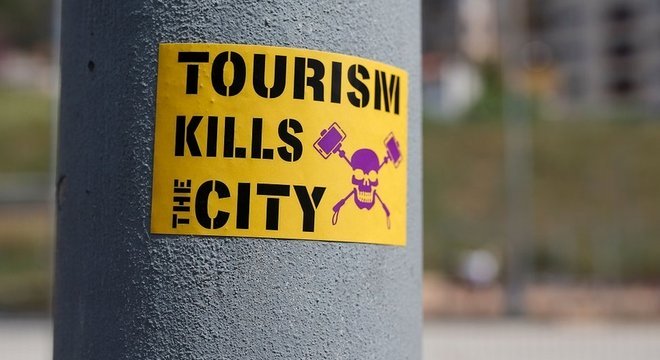 "O turismo mata a cidade", diz um adesivo colado em um poste, em Barcelona