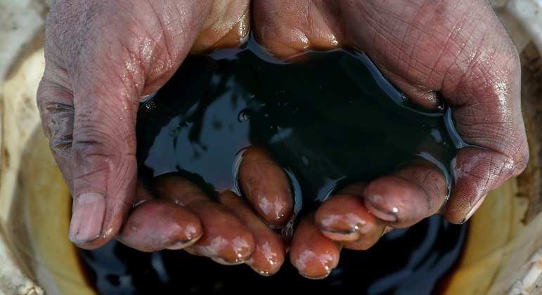 Funcionário segura amostra de petróleo bruto no campo de Yarakt, na região de Irkutsk, Rússia
