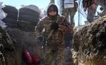 Um soldado ucraniano corre para uma trincheira militar enquanto um caça russo voa ao lado da escola militar atingida por foguetes russos na sexta-feira (18)