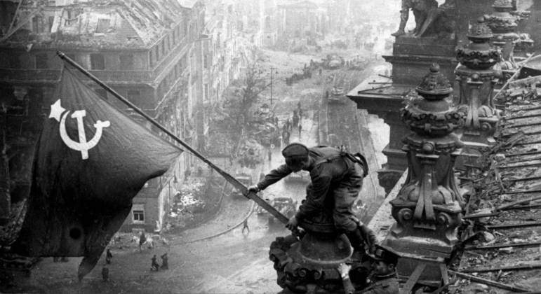 Soldados soviéticos estendem bandeira do país na recém-conquistada Berlim, em 1945